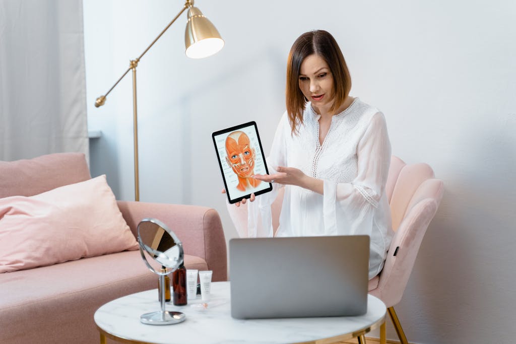 Woman demonstrating skin care procedure using a tablet during a video call.